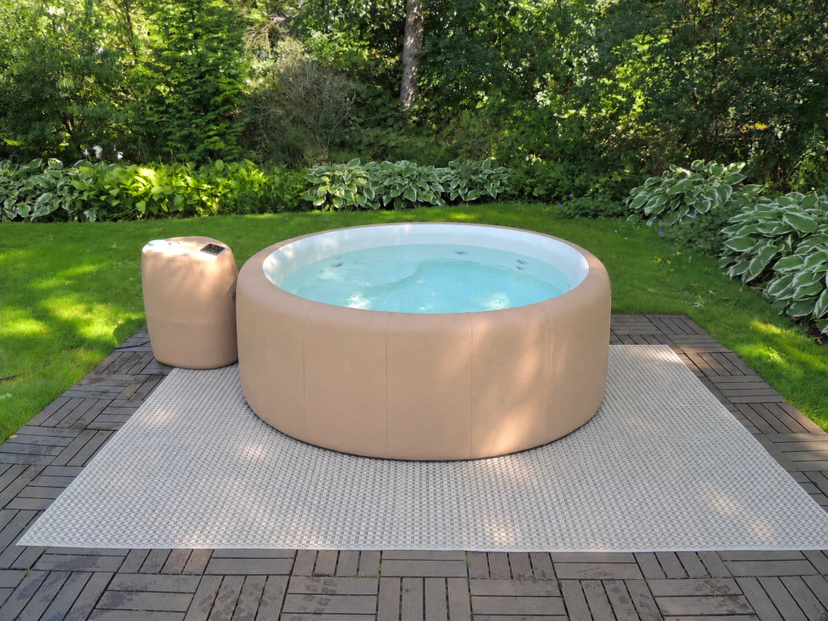 Open tan Legacy spa on a deck in a leafy garden.