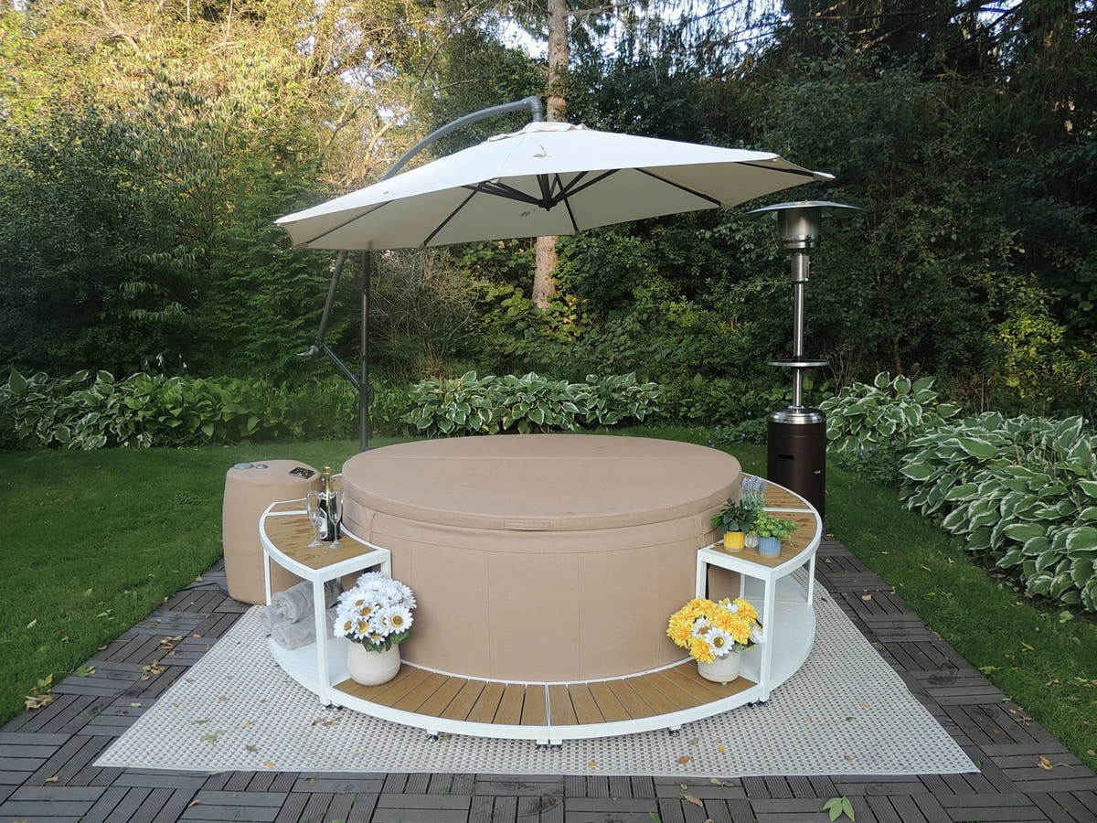 White-framed Saratoga surround around a covered tan spa in a garden.